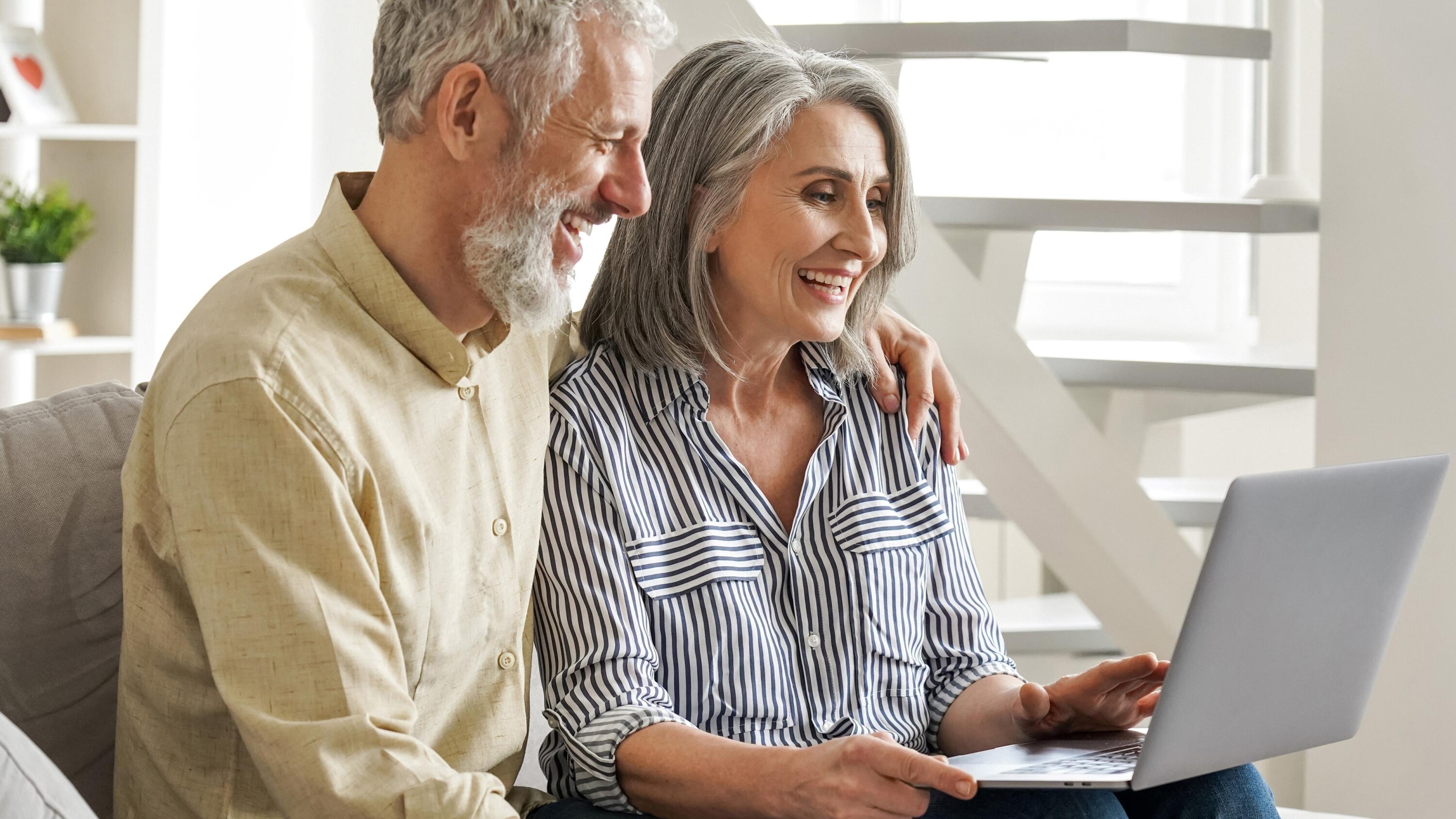 A smiling couple is looking at Mass Advantage on a laptop.