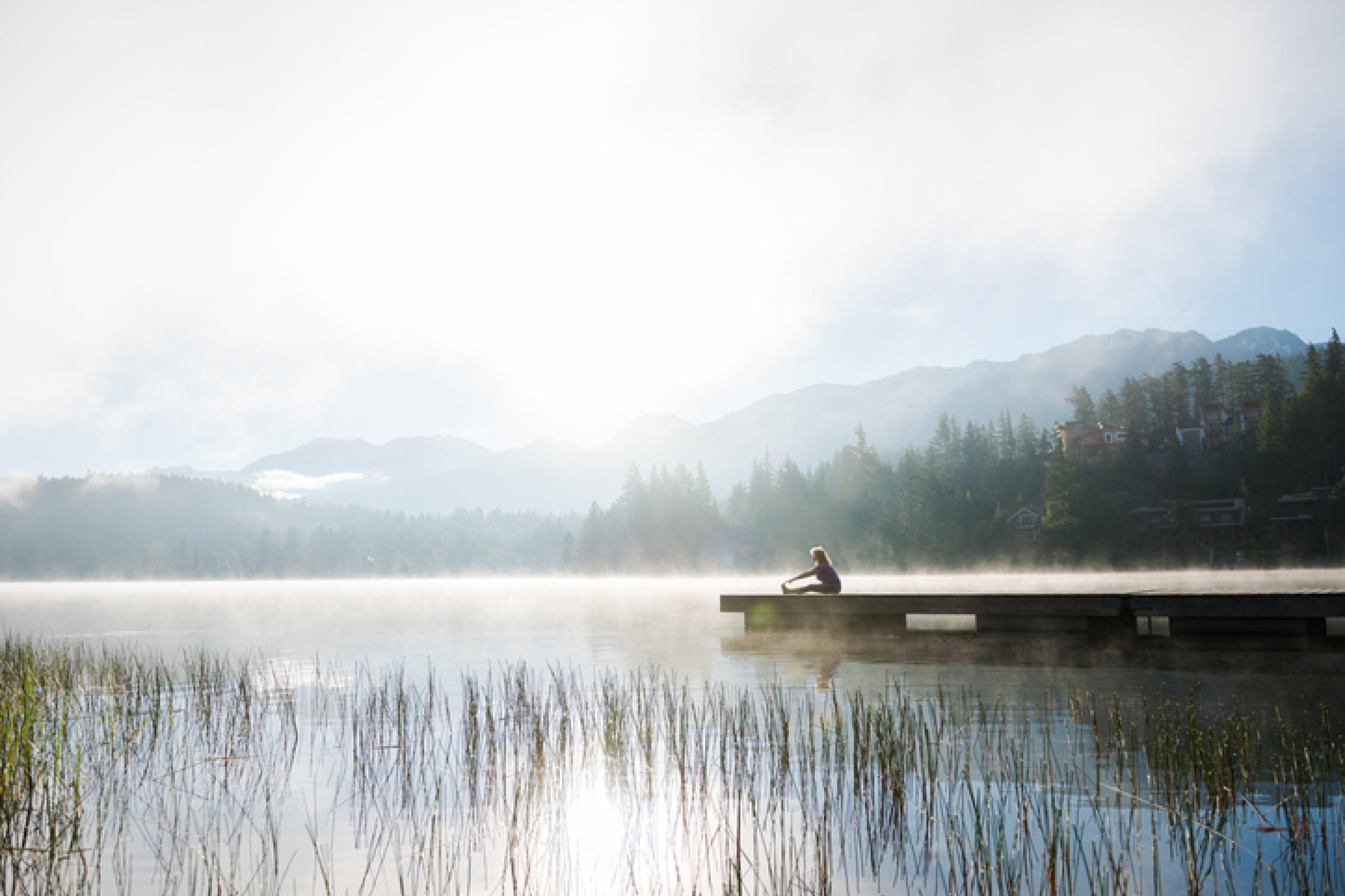 Older woman doing yoga on lake 