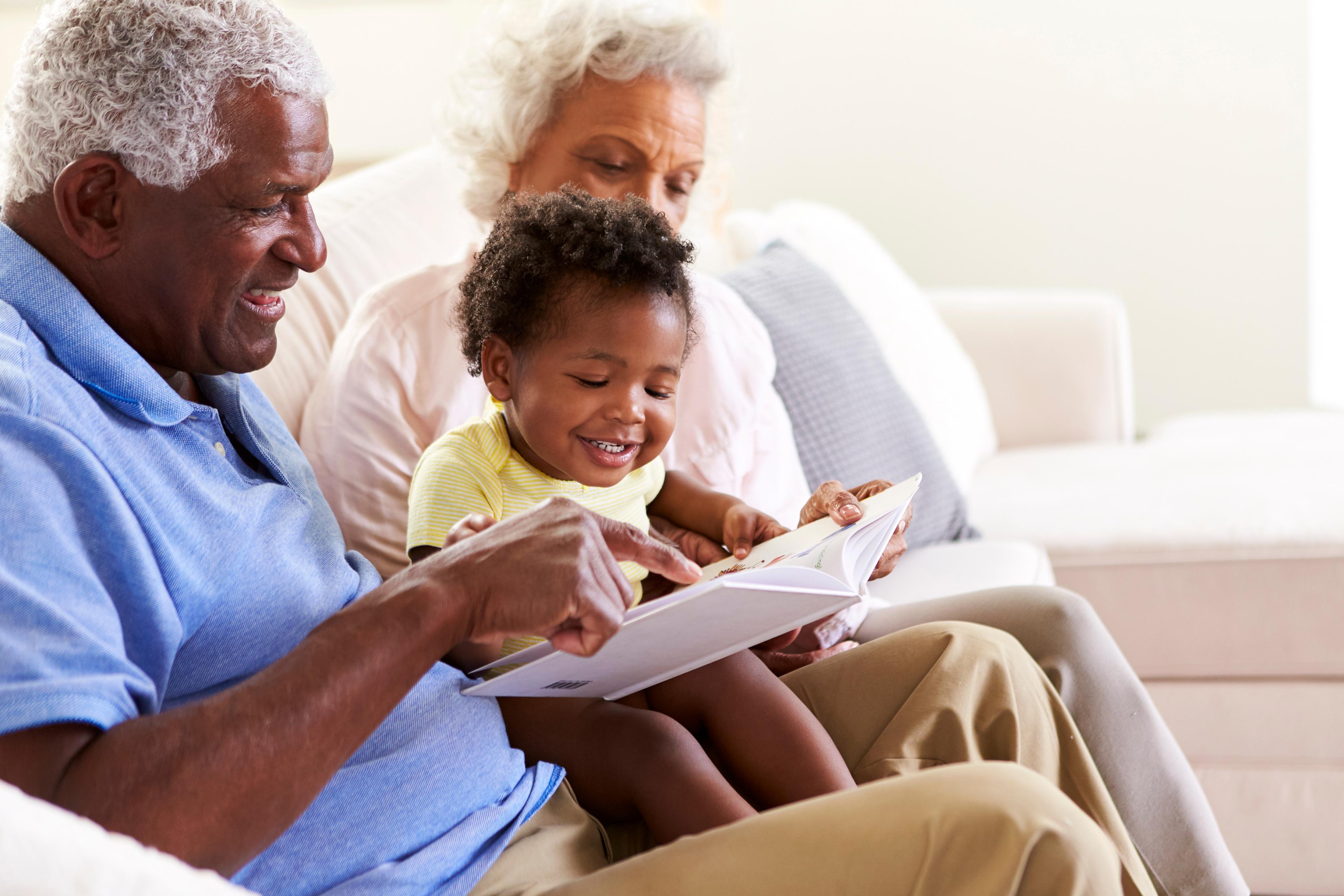 Man and woman reading to their grandchild 